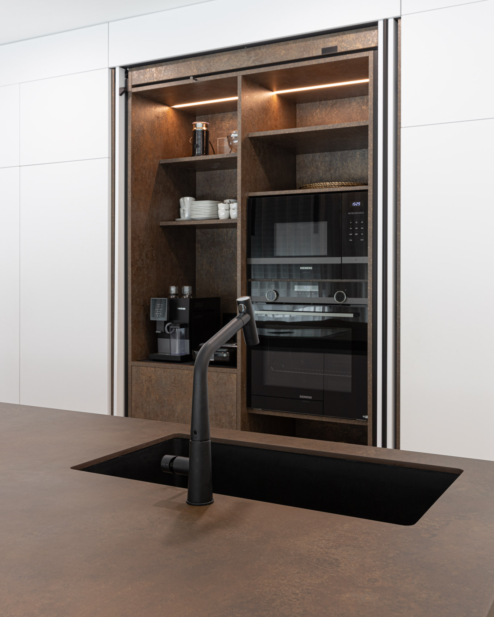 Cozinha branca com ilha Laminam em Portimão, Algarve Cozinha com zona de pequenos-almoços com portas reentrantes, que esconde também forno e micro-ondas. Lava-louça e misturadora Franke.