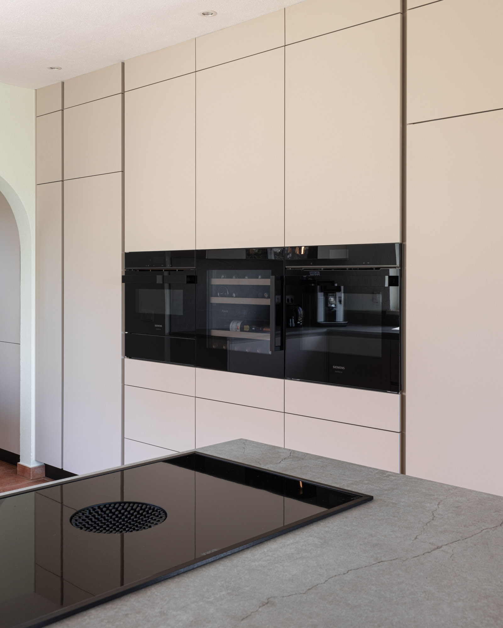 Cozinha bege com equipamentos Siemens studioLine e garrafeira Pando Cozinha bege com forno, micro-ondas e gaveta de aquecimento Siemens studioLine e garrafeira Pando.