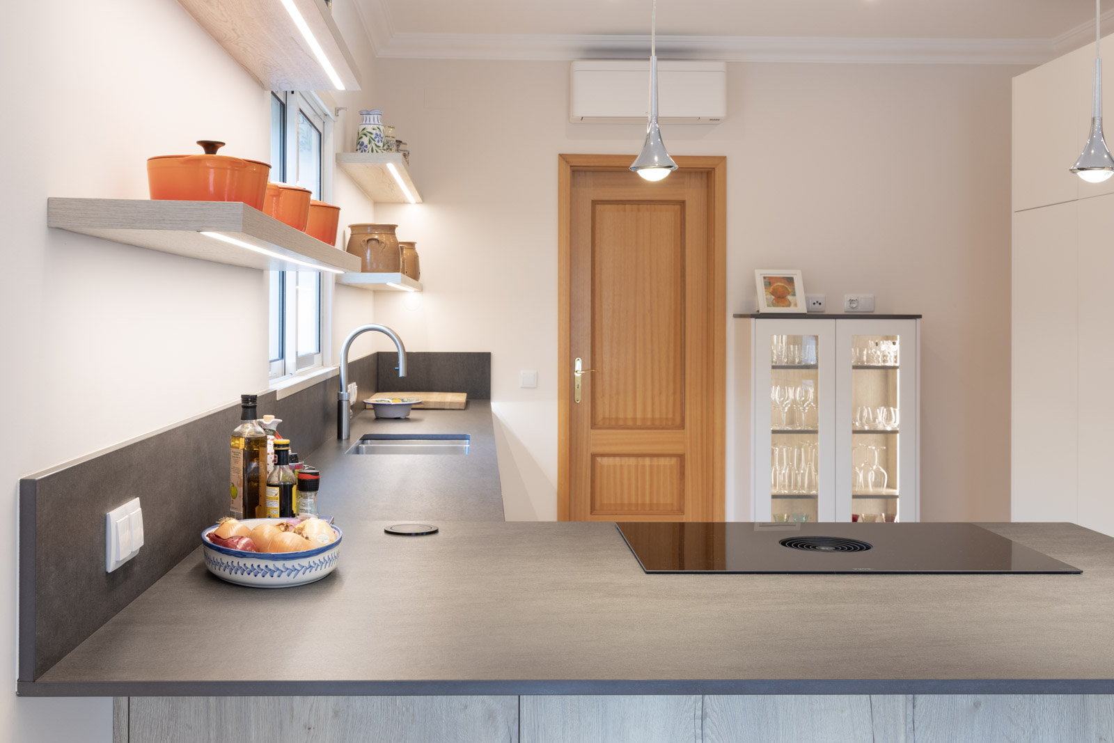 Cozinha JMQ de Luxo em Almancil, Algarve, com frentes lacadas em cinza suave mate, vitrine iluminada, sistema BORA M Pure e bancada em Dekton Bromo.