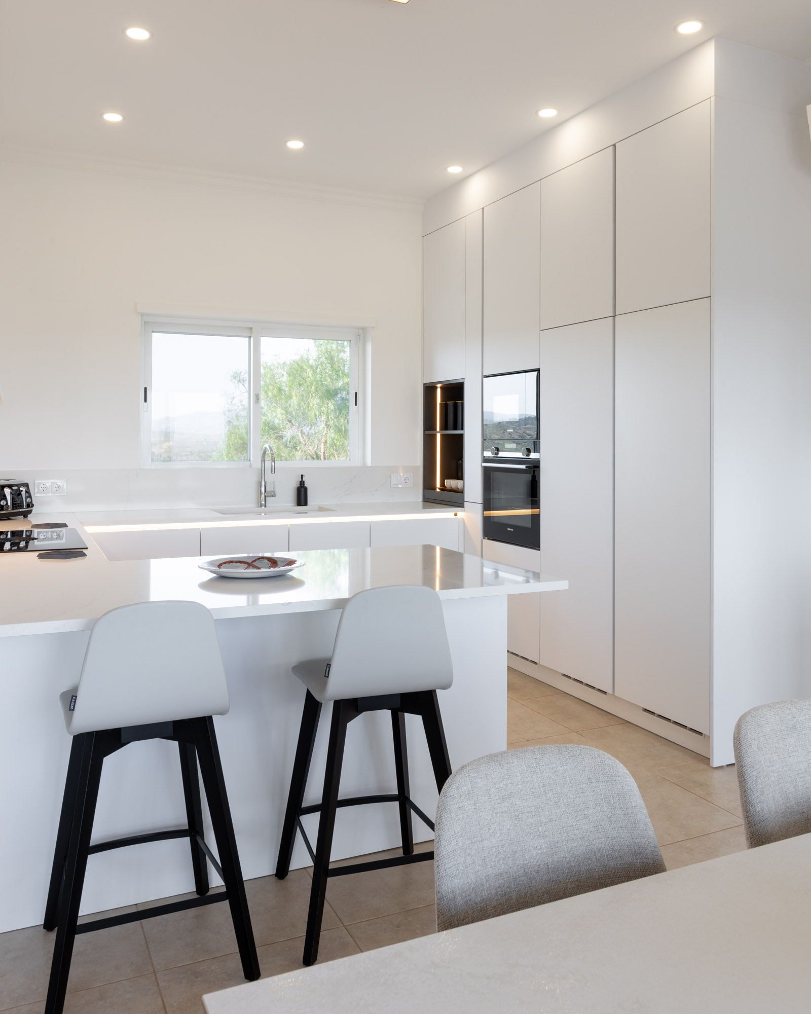 Cozinha branca com bancada Silestone Calacatta Gold, sistema BORA Pure e Quooker.