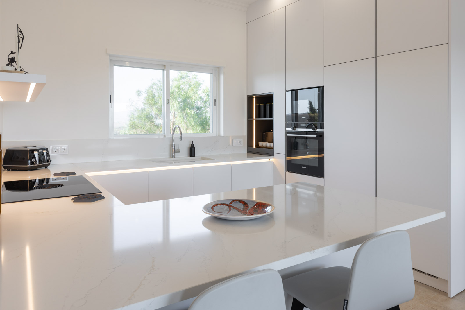 Cozinha branca com bancada Silestone Calacatta Gold, sistema BORA Pure e Quooker.